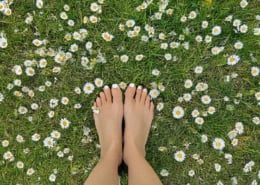 A woman's feet on a daisy covered lawn