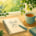 An illustration of a table in a window in summer with a note book and a cup of tea